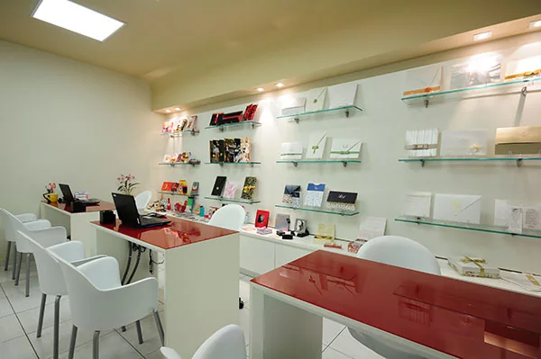 Showroom da Eden Gráfica: prateleiras com amostras de impressos e balcão vermelho de atendimento