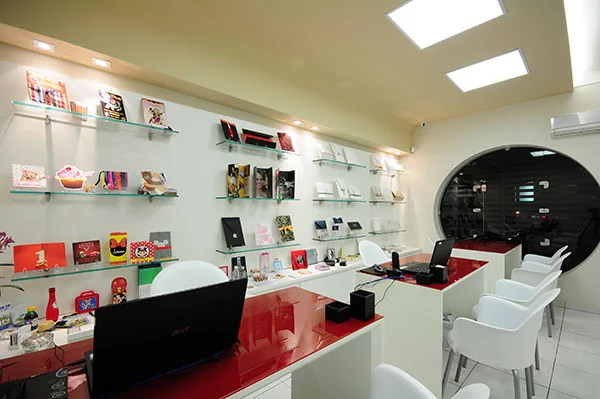 Showroom visto de outro ângulo, com cadeiras brancas em volta do balcão de atendimento