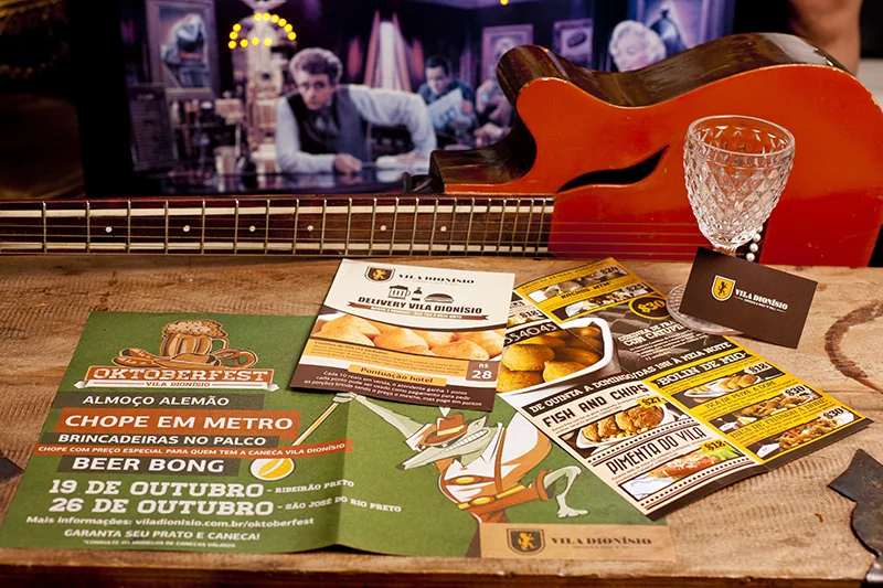 Panfleto de bar impresso em quatro cores, anunciando chope em metro e beer pong, com um violão ao fundo